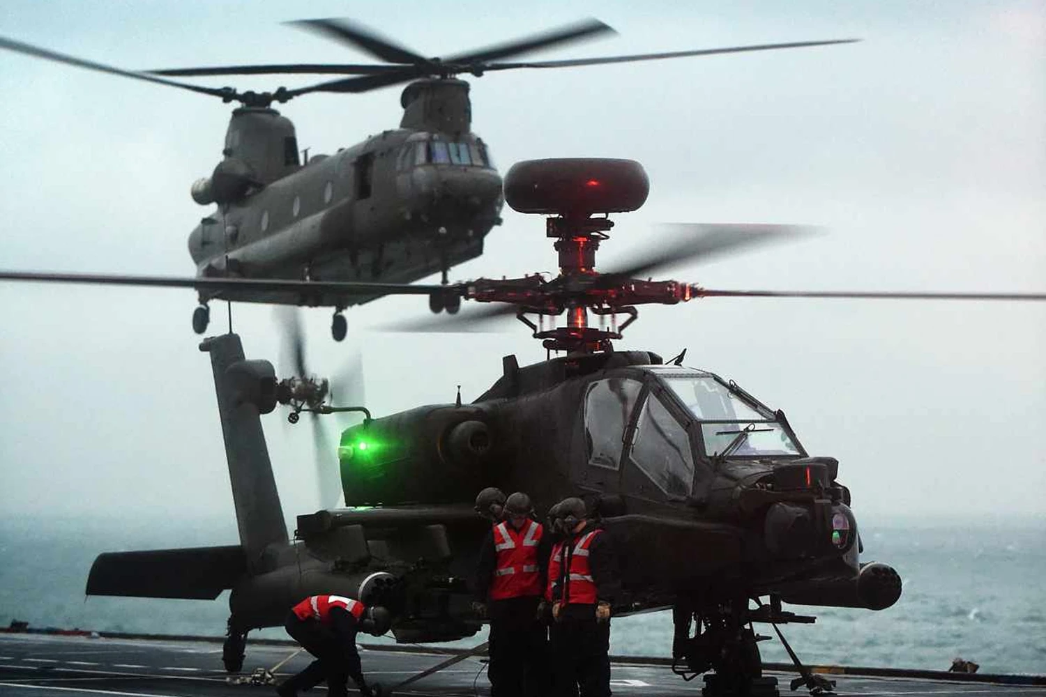 Um Apache estacionado no convés de voo do HMS Ocean; ao fundo um Chinook se aproxima (Divulgação)